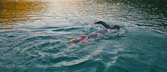 Image showing A professional triathlete trains with unwavering dedication for an upcoming competition at a lake, emanating a sense of athleticism and profound commitment to excellence.