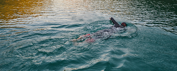 Image showing A professional triathlete trains with unwavering dedication for an upcoming competition at a lake, emanating a sense of athleticism and profound commitment to excellence.