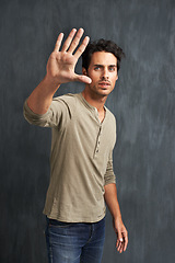 Image showing Serious, hand and portrait of man with stop for no, wait or rejection expression by wall. Upset, scared and young male person from Canada with casual style and fear palm gesture by gray background.