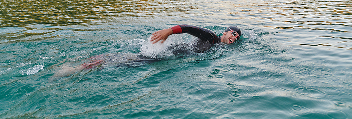 Image showing A professional triathlete trains with unwavering dedication for an upcoming competition at a lake, emanating a sense of athleticism and profound commitment to excellence.