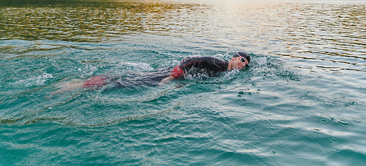 Image showing A professional triathlete trains with unwavering dedication for an upcoming competition at a lake, emanating a sense of athleticism and profound commitment to excellence.