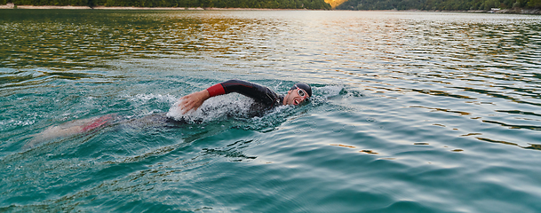 Image showing A professional triathlete trains with unwavering dedication for an upcoming competition at a lake, emanating a sense of athleticism and profound commitment to excellence.