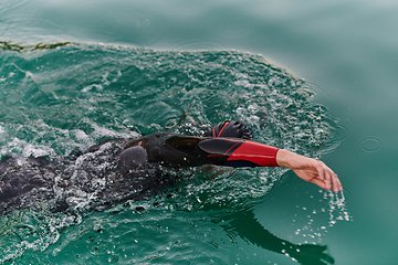 Image showing A professional triathlete trains with unwavering dedication for an upcoming competition at a lake, emanating a sense of athleticism and profound commitment to excellence.