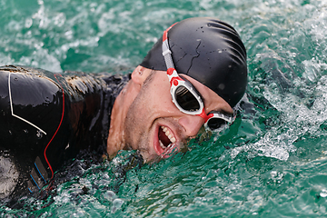 Image showing A professional triathlete trains with unwavering dedication for an upcoming competition at a lake, emanating a sense of athleticism and profound commitment to excellence.