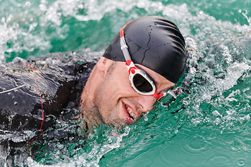 Image showing A professional triathlete trains with unwavering dedication for an upcoming competition at a lake, emanating a sense of athleticism and profound commitment to excellence.