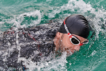 Image showing A professional triathlete trains with unwavering dedication for an upcoming competition at a lake, emanating a sense of athleticism and profound commitment to excellence.