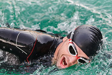 Image showing A professional triathlete trains with unwavering dedication for an upcoming competition at a lake, emanating a sense of athleticism and profound commitment to excellence.