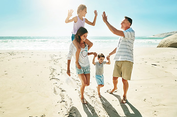 Image showing Parents, children and beach for high five happy or summer travel vacation, ocean sunshine or family development. Man, woman and kids on sand for holiday relax walking or outdoor, clean air or smile