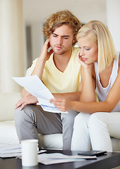 Image showing Couple, confused for bills and reading documents on sofa with debt, financial planning or budget risk and stress at home. Serious man and woman thinking of loan, house expenses or mortgage paperwork