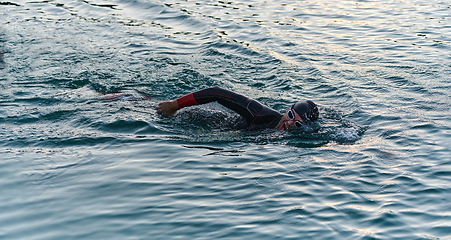 Image showing A professional triathlete trains with unwavering dedication for an upcoming competition at a lake, emanating a sense of athleticism and profound commitment to excellence.