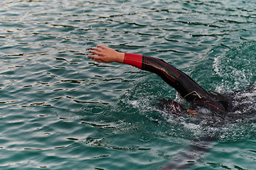 Image showing A professional triathlete trains with unwavering dedication for an upcoming competition at a lake, emanating a sense of athleticism and profound commitment to excellence.