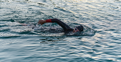 Image showing A professional triathlete trains with unwavering dedication for an upcoming competition at a lake, emanating a sense of athleticism and profound commitment to excellence.