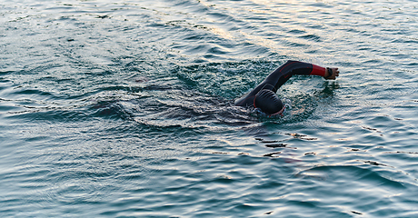 Image showing A professional triathlete trains with unwavering dedication for an upcoming competition at a lake, emanating a sense of athleticism and profound commitment to excellence.