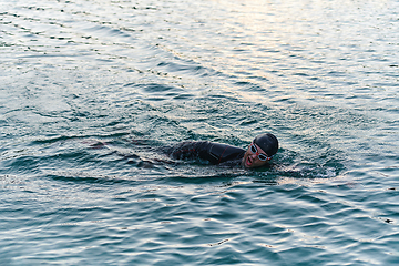 Image showing A professional triathlete trains with unwavering dedication for an upcoming competition at a lake, emanating a sense of athleticism and profound commitment to excellence.