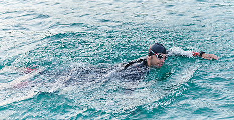 Image showing A professional triathlete trains with unwavering dedication for an upcoming competition at a lake, emanating a sense of athleticism and profound commitment to excellence.