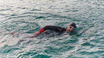 Image showing A professional triathlete trains with unwavering dedication for an upcoming competition at a lake, emanating a sense of athleticism and profound commitment to excellence.