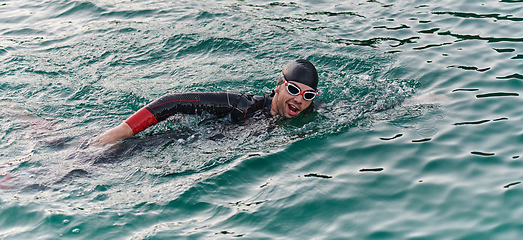 Image showing A professional triathlete trains with unwavering dedication for an upcoming competition at a lake, emanating a sense of athleticism and profound commitment to excellence.