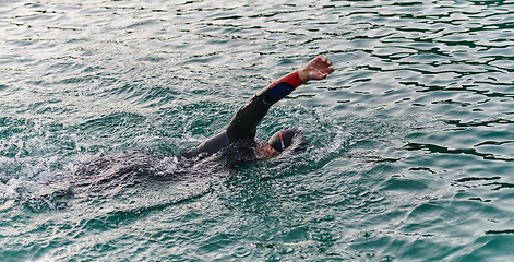 Image showing A professional triathlete trains with unwavering dedication for an upcoming competition at a lake, emanating a sense of athleticism and profound commitment to excellence.