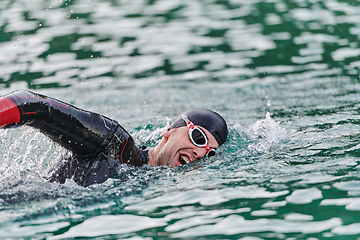 Image showing A professional triathlete trains with unwavering dedication for an upcoming competition at a lake, emanating a sense of athleticism and profound commitment to excellence.