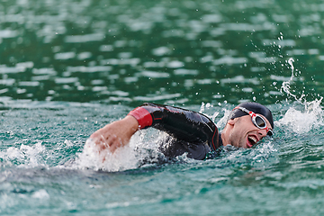 Image showing A professional triathlete trains with unwavering dedication for an upcoming competition at a lake, emanating a sense of athleticism and profound commitment to excellence.