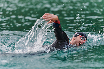 Image showing A professional triathlete trains with unwavering dedication for an upcoming competition at a lake, emanating a sense of athleticism and profound commitment to excellence.