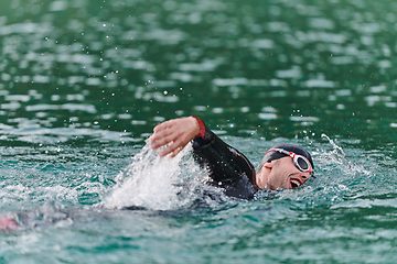 Image showing A professional triathlete trains with unwavering dedication for an upcoming competition at a lake, emanating a sense of athleticism and profound commitment to excellence.