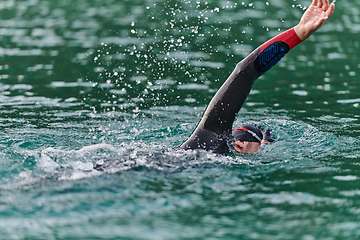 Image showing A professional triathlete trains with unwavering dedication for an upcoming competition at a lake, emanating a sense of athleticism and profound commitment to excellence.