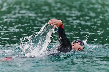 Image showing A professional triathlete trains with unwavering dedication for an upcoming competition at a lake, emanating a sense of athleticism and profound commitment to excellence.