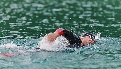 Image showing A professional triathlete trains with unwavering dedication for an upcoming competition at a lake, emanating a sense of athleticism and profound commitment to excellence.