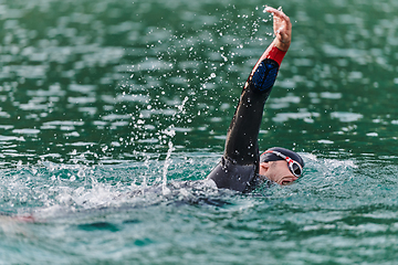 Image showing A professional triathlete trains with unwavering dedication for an upcoming competition at a lake, emanating a sense of athleticism and profound commitment to excellence.