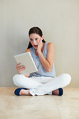 Image showing Woman, tablet and surprised on social media, news or gossip sitting against a wall at home. Shocked female person, brunette or freelancer gasping on technology for notification, alert or information