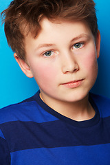 Image showing Child, portrait and closeup with blue background with fashion, stylish youth and trendy clothes in studio. Young boy, kid and face with confidence and student with modern and casual style with model