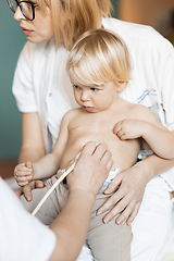 Image showing Small child being checked for heart murmur by heart ultrasound exam by cardiologist as part of regular medical checkout at pediatrician.