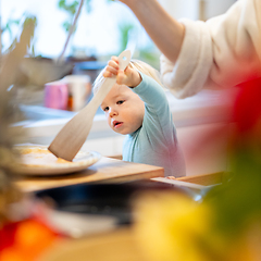 Image showing Mother and little toddler baby boy making pancakes for breakfast together in domestic kitchen. Family, lifestyle, domestic life, food, healthy eating and people concept.