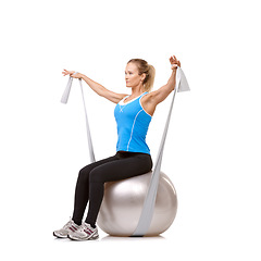Image showing Yoga ball, resistance band and woman doing exercise in studio for health, wellness and body care. Sports, fitness and young female person from Canada with arms workout or training by white background