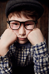 Image showing Portrait, glasses and bored kid, sad expression and thinking of depression. Tired face, nerd and young boy child in hat, geek in eyewear or exhausted with learning, serious or stress in New Zealand