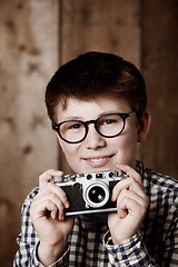 Image showing Portrait, child and vintage for camera with happiness, mockup and positive in glasses by backdrop. Boy, smile face and nerd with photography in retro clothes and eyewear for creative kids with vision