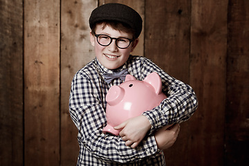 Image showing Young child, hugging and piggy bank in portrait in studio background, retro money safe and cash savings in youth. Boy, smile and face for coin banking in vintage fashion and happy for dollars profit