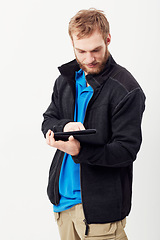 Image showing Man, tablet and typing in studio, thinking and notes with click, scroll and reading by white background. Person, digital touchscreen and press for blog, email notification or social network on app