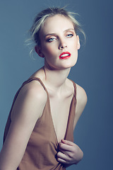 Image showing Red lipstick, fashion and face of woman on blue background with makeup, cosmetics and beauty in studio. Model, aesthetic and person with confidence, pride and serious in trendy or stylish clothes