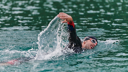 Image showing A professional triathlete trains with unwavering dedication for an upcoming competition at a lake, emanating a sense of athleticism and profound commitment to excellence.