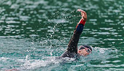 Image showing A professional triathlete trains with unwavering dedication for an upcoming competition at a lake, emanating a sense of athleticism and profound commitment to excellence.