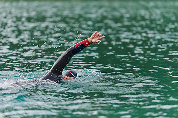 Image showing A professional triathlete trains with unwavering dedication for an upcoming competition at a lake, emanating a sense of athleticism and profound commitment to excellence.