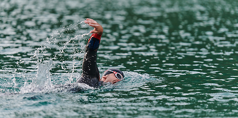 Image showing A professional triathlete trains with unwavering dedication for an upcoming competition at a lake, emanating a sense of athleticism and profound commitment to excellence.