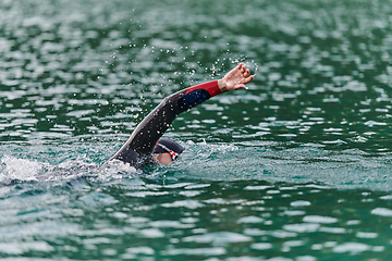 Image showing A professional triathlete trains with unwavering dedication for an upcoming competition at a lake, emanating a sense of athleticism and profound commitment to excellence.