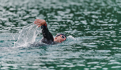 Image showing A professional triathlete trains with unwavering dedication for an upcoming competition at a lake, emanating a sense of athleticism and profound commitment to excellence.