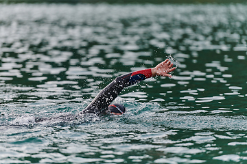 Image showing A professional triathlete trains with unwavering dedication for an upcoming competition at a lake, emanating a sense of athleticism and profound commitment to excellence.