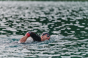 Image showing A professional triathlete trains with unwavering dedication for an upcoming competition at a lake, emanating a sense of athleticism and profound commitment to excellence.