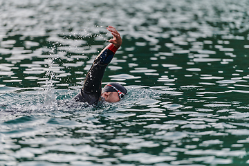 Image showing A professional triathlete trains with unwavering dedication for an upcoming competition at a lake, emanating a sense of athleticism and profound commitment to excellence.