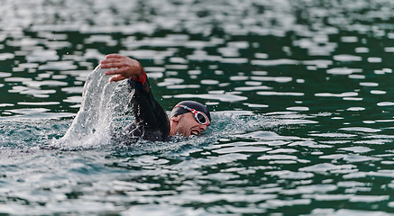 Image showing A professional triathlete trains with unwavering dedication for an upcoming competition at a lake, emanating a sense of athleticism and profound commitment to excellence.